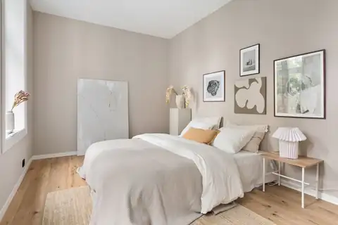 Bedroom with warm beige walls, white bedding and framed art