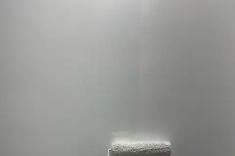 Paint roller putting light gray paint on a wall